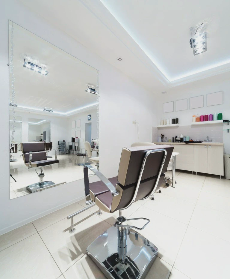 Stanowisko w nowoczesnym salonie fryzjerskim z lustrem, fotelem i półkami z kosmetykami